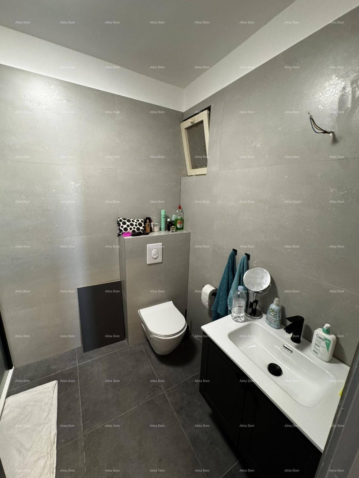 Modernes Badezimmer mit grauen Fliesen, wandhängendem WC und Einzelwaschbecken.