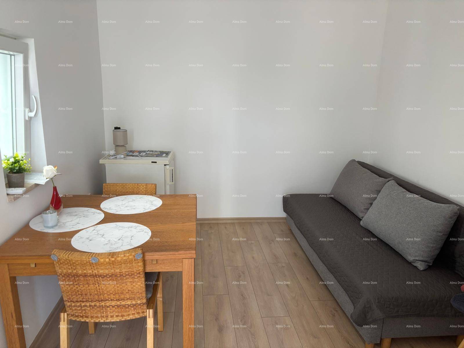 Heller Wohn- und Essbereich mit Laminatboden, einem Holztisch und einer kleinen Küchenzeile.