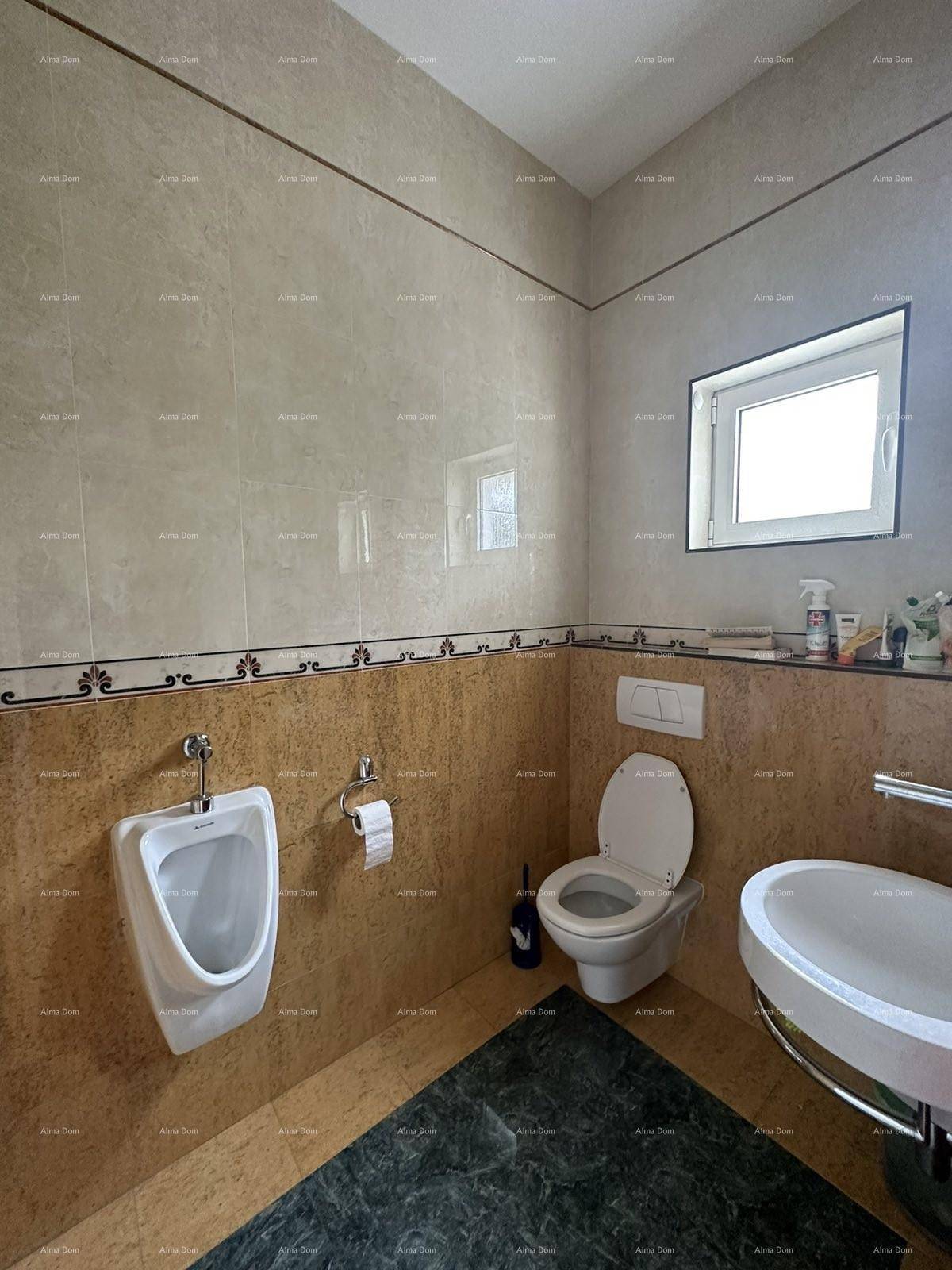 Gäste-WC mit Urinal, Toilette, Waschbecken und beigen sowie braunen Fliesen.