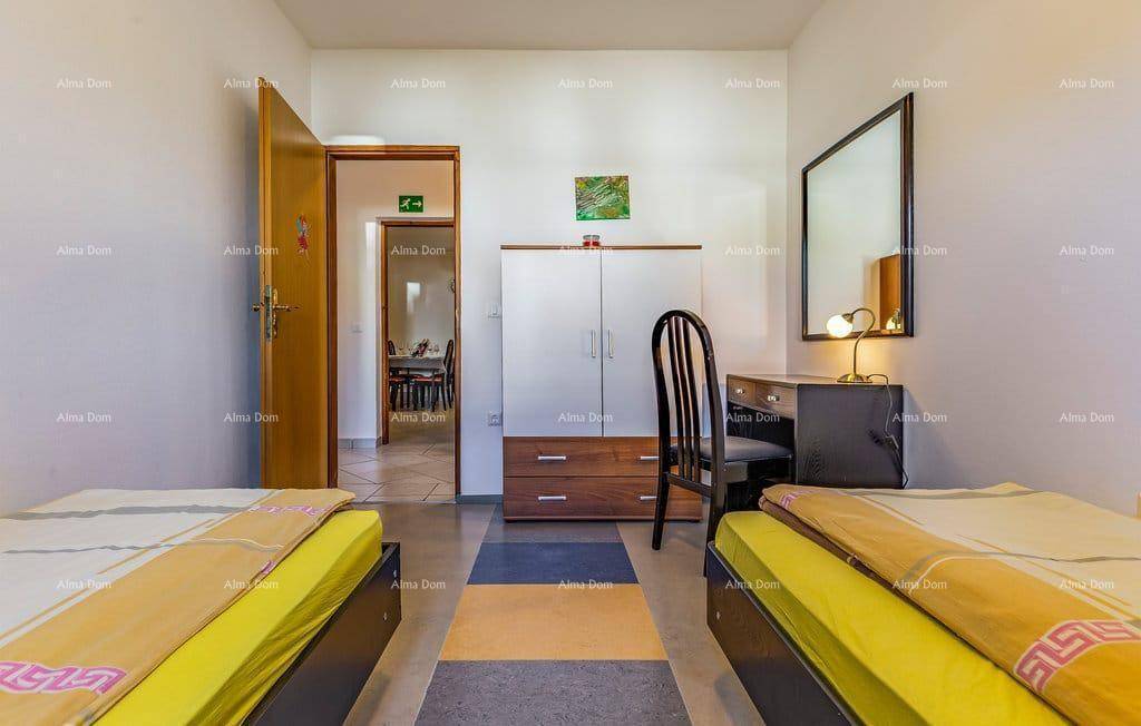 Helles Schlafzimmer mit zwei Einzelbetten, Schreibtisch und Blick in den angrenzenden Flur.