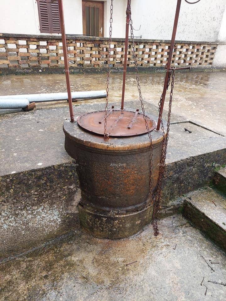 Nahaufnahme eines alten gemauerten Brunnens mit Metallabdeckung und Ketten auf einer Dachterrasse.