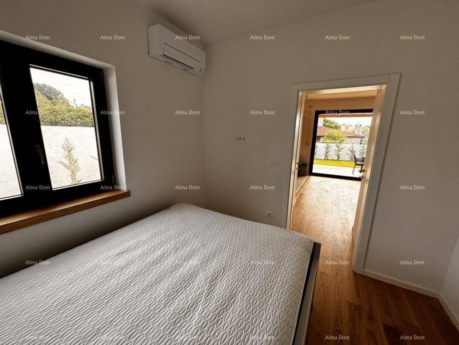 Schlafzimmer mit Holzboden, weißem Bett und Fenster mit Blick ins Grüne.