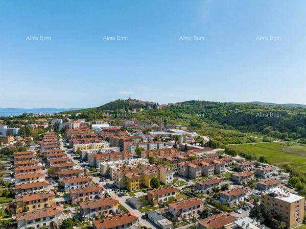 Weitläufige Luftaufnahme einer Küstenstadt mit vielen Häusern und grünen Hügeln.