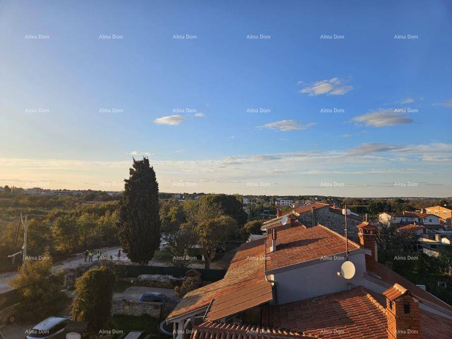 Panoramablick über die roten Dächer der Häuser und die umliegende grüne Landschaft bei Sonnenuntergang.