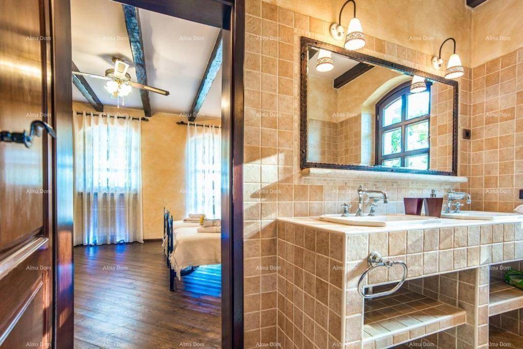Badezimmer mit Doppelwaschbecken, gefliesten Wänden und Blick in das angrenzende Schlafzimmer.