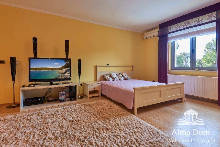 Geräumiges Schlafzimmer mit Holzboden, Teppich, gelben Wänden und Klimaanlage.