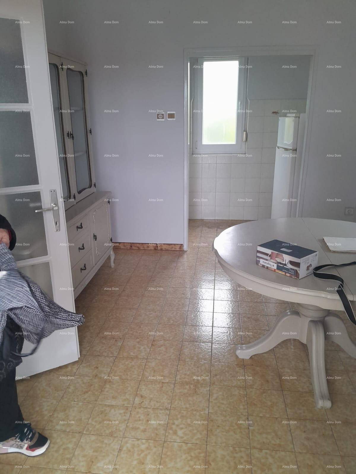 Essbereich mit rundem weißen Tisch, einem Schrank und gemusterten Fliesen, angrenzend an die Küche.