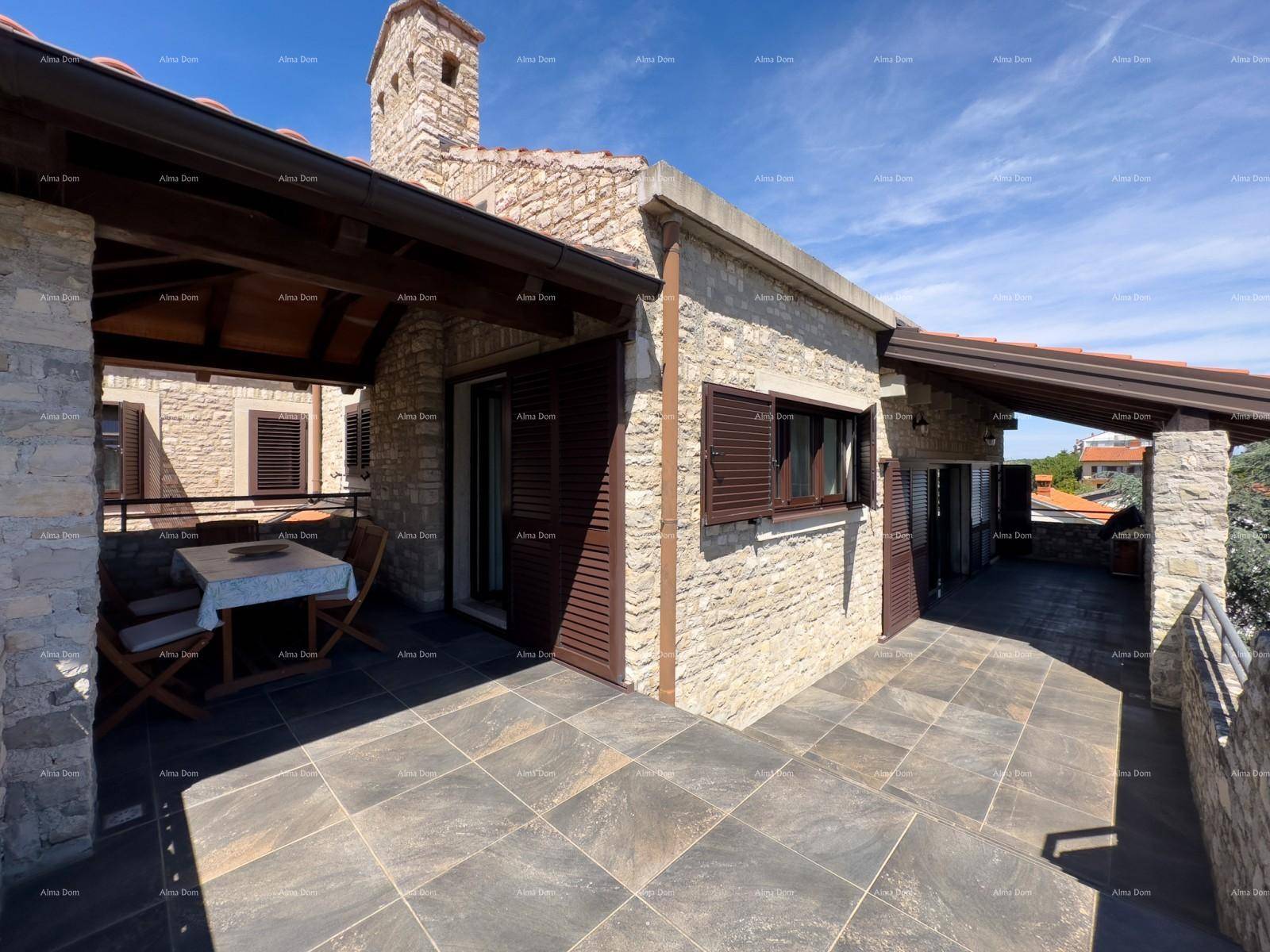 Traditionelles Steinhaus mit großer gefliester Terrasse und Holzbalken.