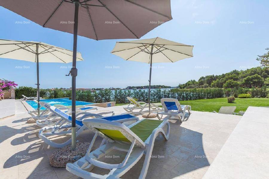 Entspannungsbereich am Pool mit bequemen Liegestühlen und Sonnenschirmen, direkt am Meer gelegen.