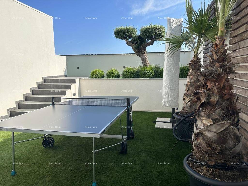 Gartenbereich mit Tischtennisplatte, Kunstrasen und Treppenaufgang zu weiteren Ebenen.