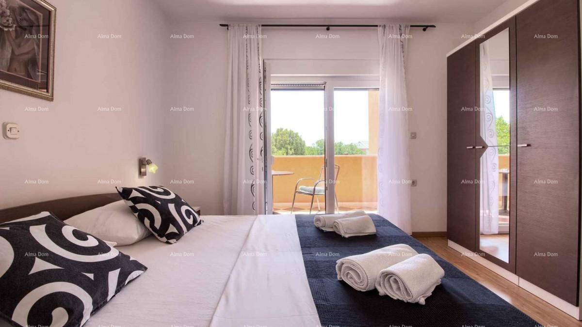 Schlafzimmer mit Doppelbett, Kleiderschrank und Zugang zu einem Balkon mit Sitzgelegenheiten.