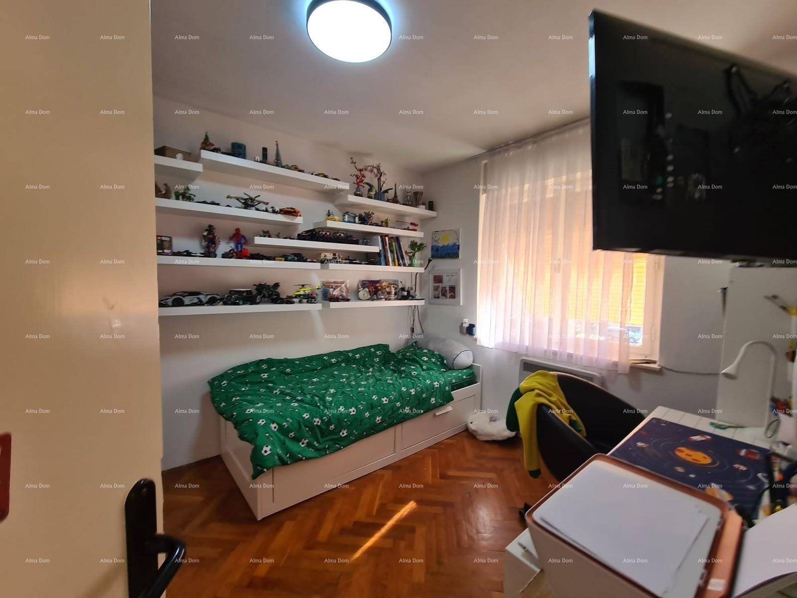 Kinderzimmer mit Bett, Schränken und Regalen für Spielzeug und Bücher.