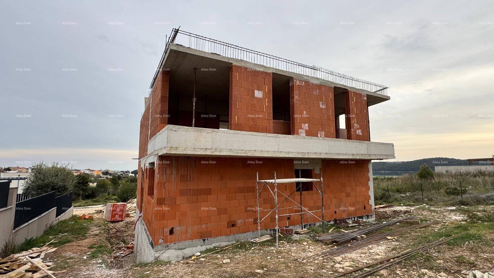 Rohbau eines modernen Hauses mit Ziegelwänden und Betonstrukturen, umgeben von Baustelle und Natur.