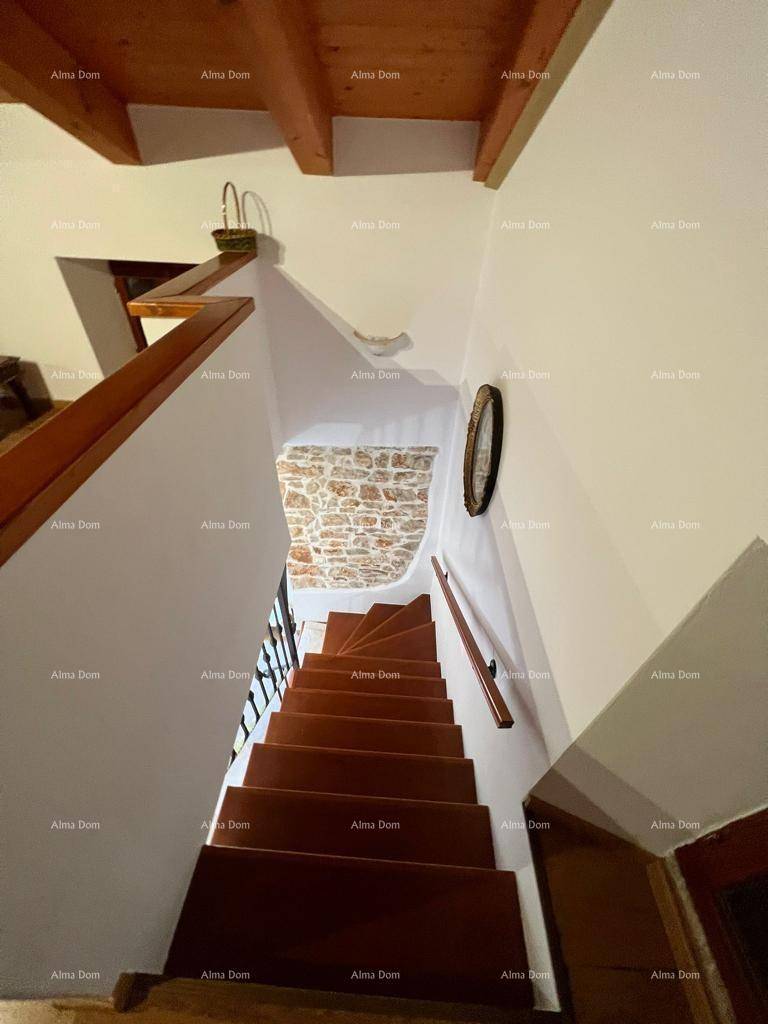 Holztreppe mit weiß gestrichenen Wänden und Steinakzenten im Treppenhaus.