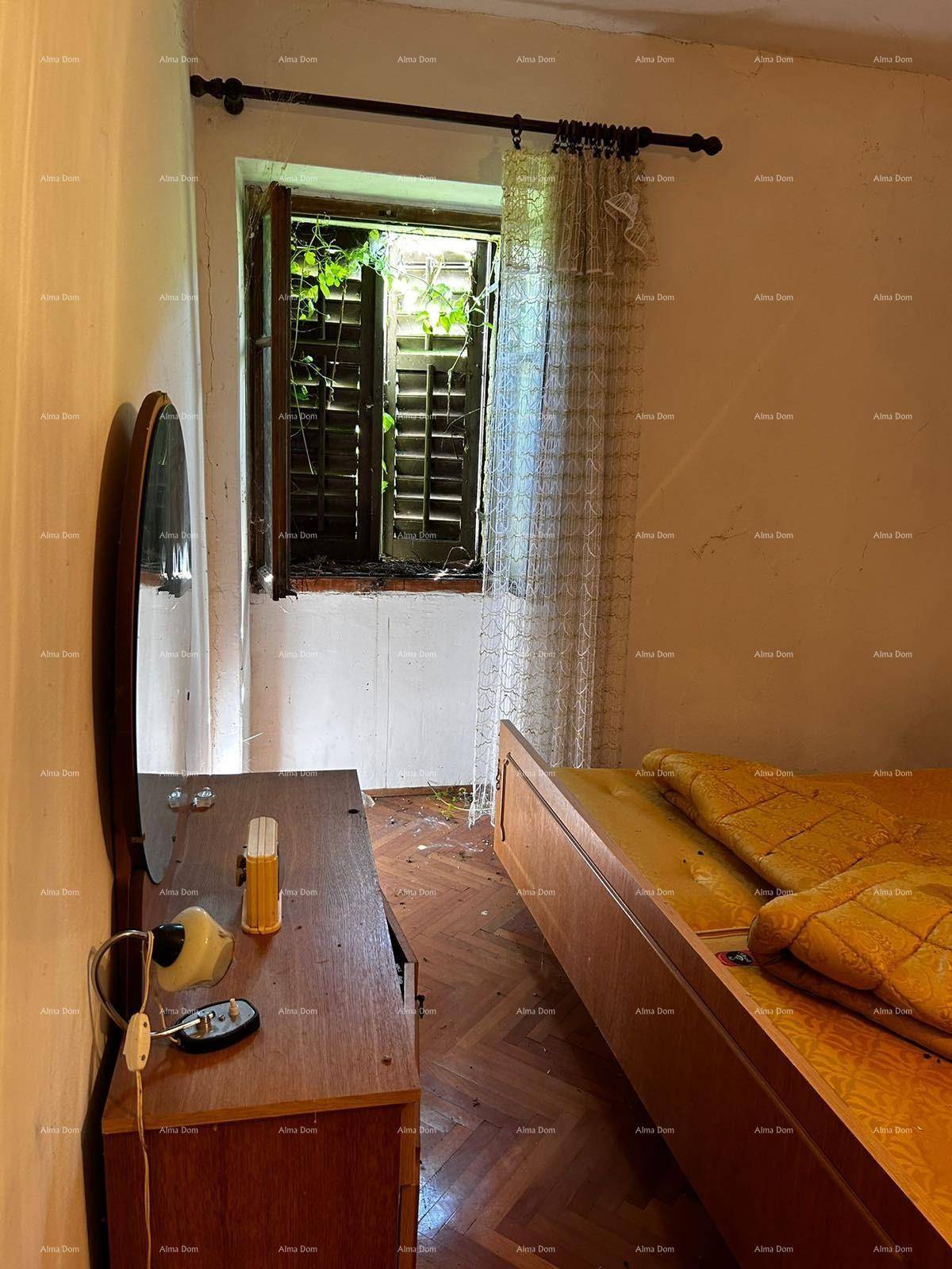 Dunkles Schlafzimmer mit Holzbett, Frisiertisch und Fenster mit Blick ins Grüne.