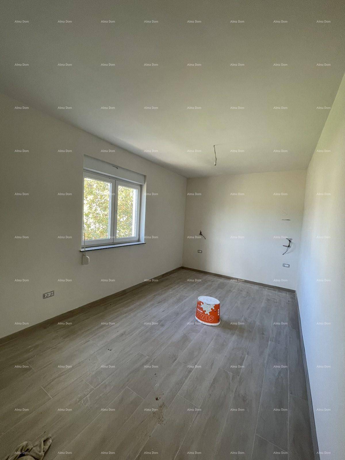 Heller, unmöblierter Raum mit großen Fliesen in Holzoptik und einem Fenster, das Tageslicht hereinlässt.