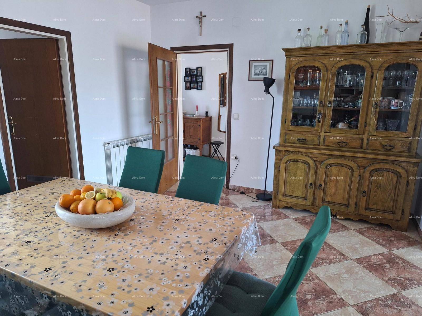 Essbereich mit großem Holztisch, grünen Stühlen und traditionellem Holzschrank.