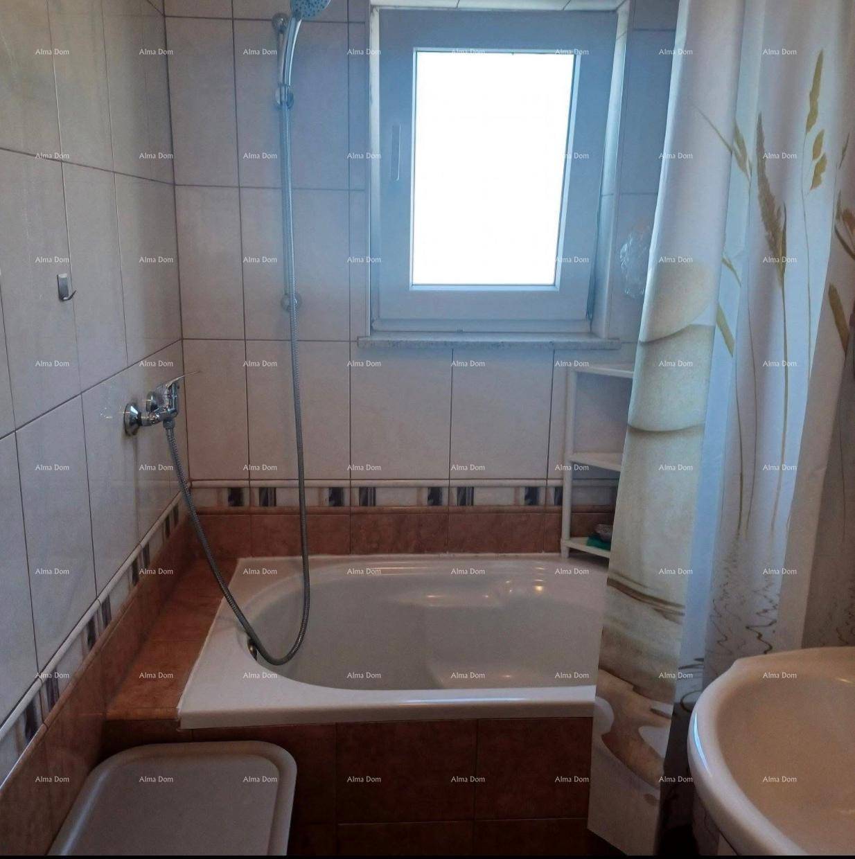 Badezimmer mit Badewanne, Duschvorhang und einem Fenster für natürliche Belüftung und Helligkeit.