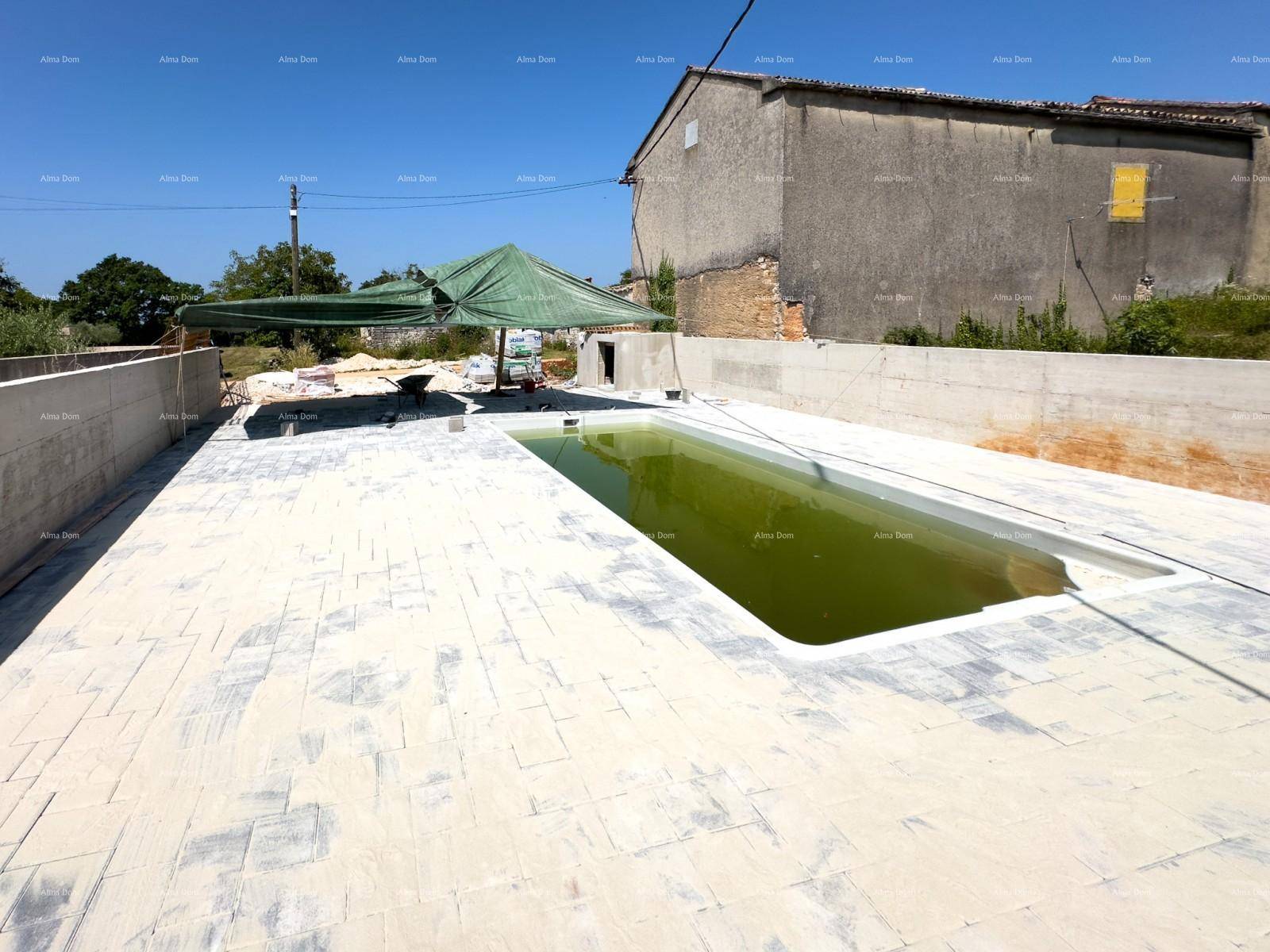 Großer Außenbereich mit Pool in Bau, gepflasterter Fläche und einem Gebäude im Hintergrund an einem sonnigen Tag.
