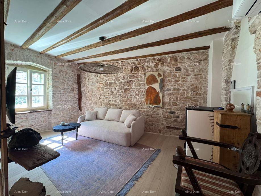 Gemütliches Wohnzimmer mit Steinwänden, Holzbalkendecke und beigem Sofa, ideal zum Entspannen.
