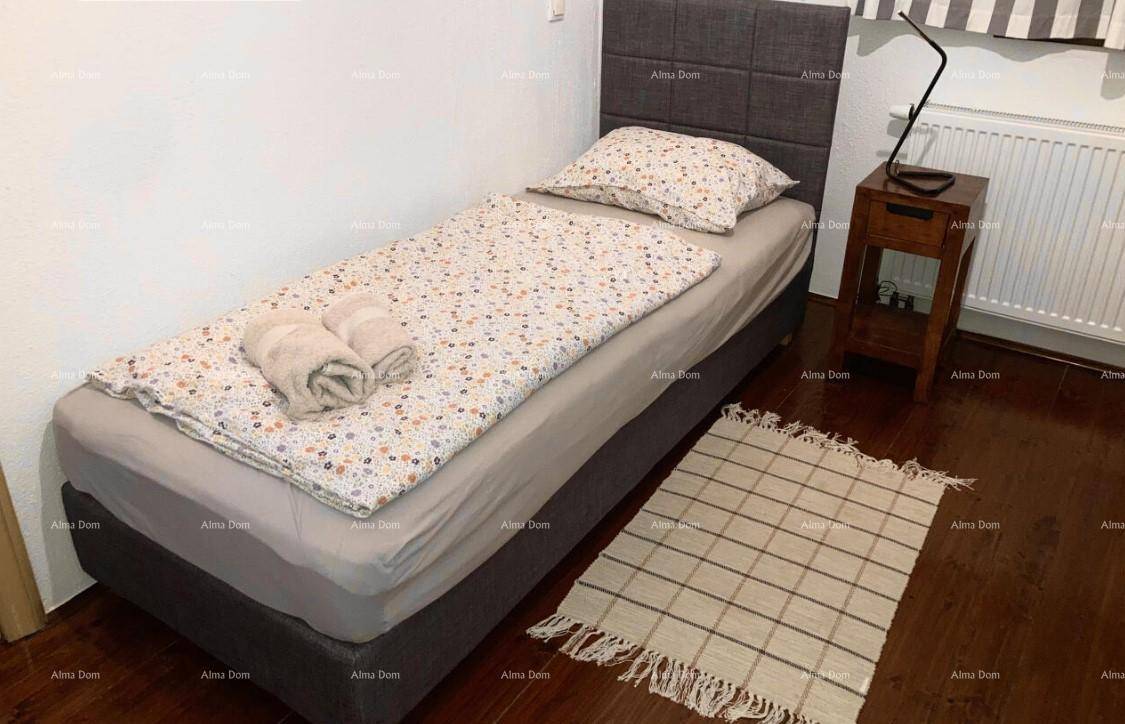 Gemütliches Schlafzimmer mit Einzelbett, gemusterter Bettwäsche und einem rustikalen Nachttisch.