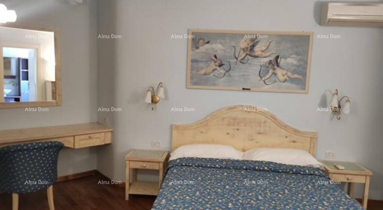 Schlafzimmer mit hellem Holzdoppelbett, Nachttischen, Schminktisch und Klimaanlage.