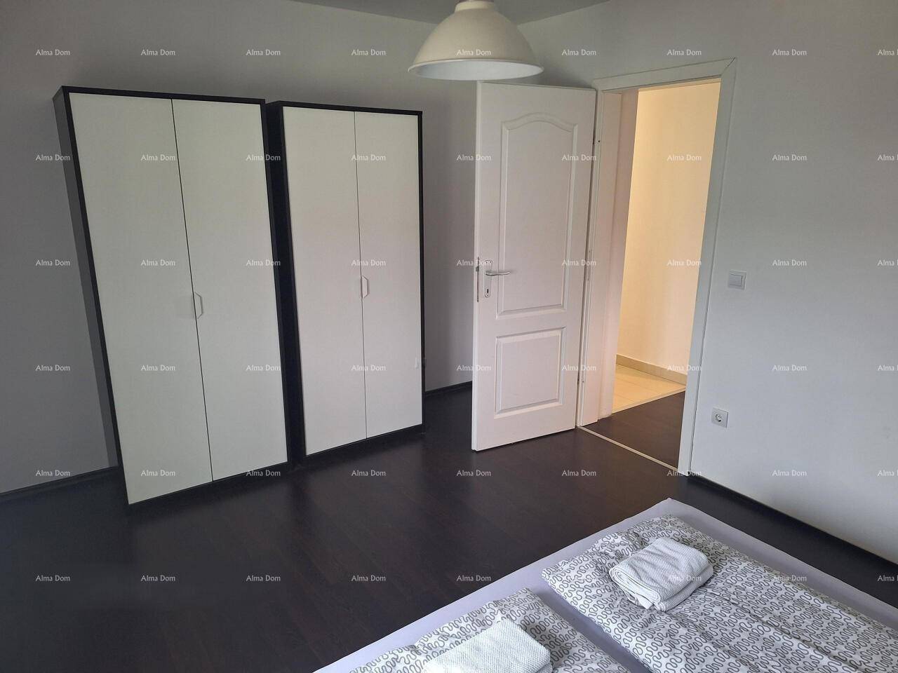 Schlafzimmer mit zwei weißen Kleiderschränken und dunklem Boden, bietet ausreichend Stauraum.
