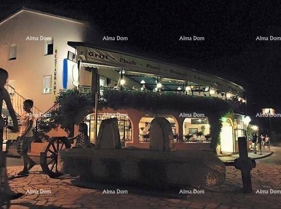 Nachtaufnahme des beleuchteten Restaurants mit Gästen und einem dekorativen Brunnen im Vordergrund.