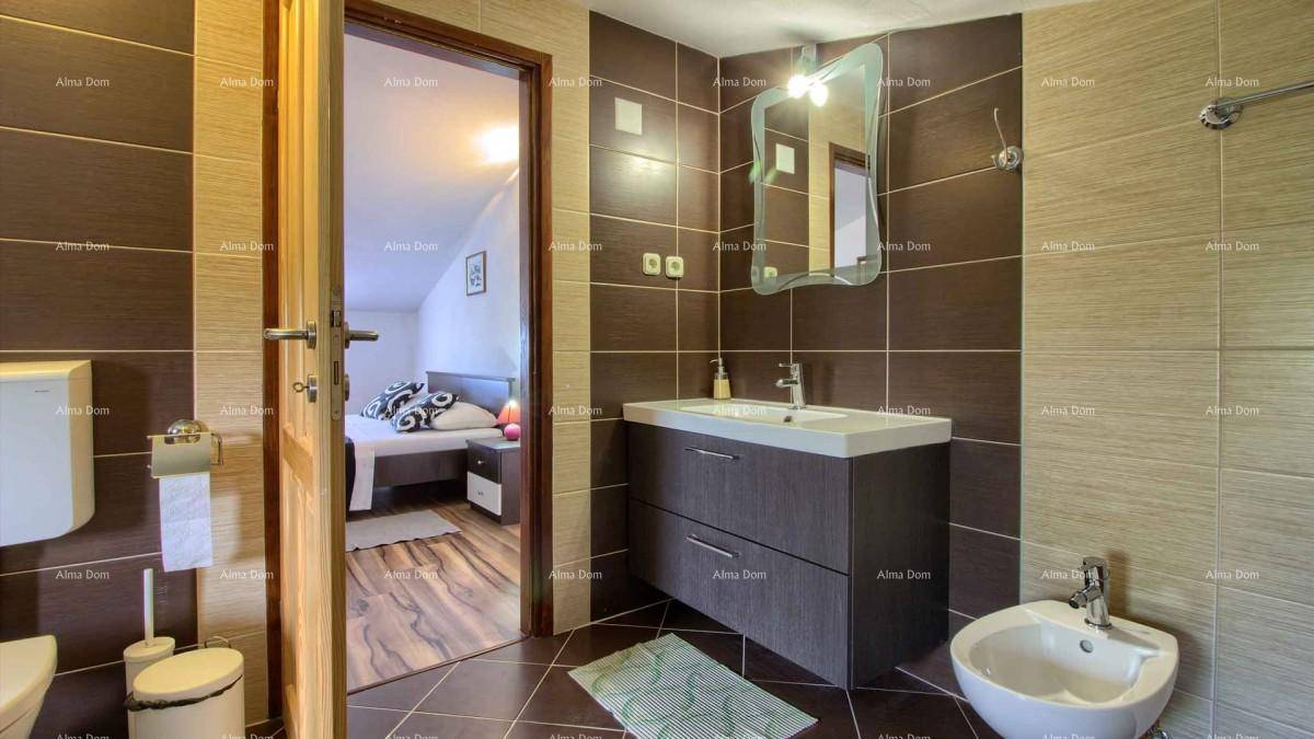 Badezimmer mit Waschbecken, WC, Bidet und Fliesen, mit Blick in das angrenzende Schlafzimmer.
