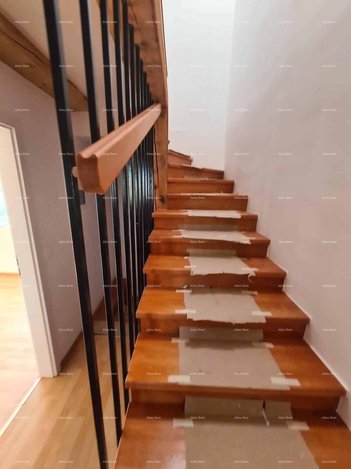 Holztreppe mit schwarzen Metallgeländern, die in die oberen Stockwerke führt.
