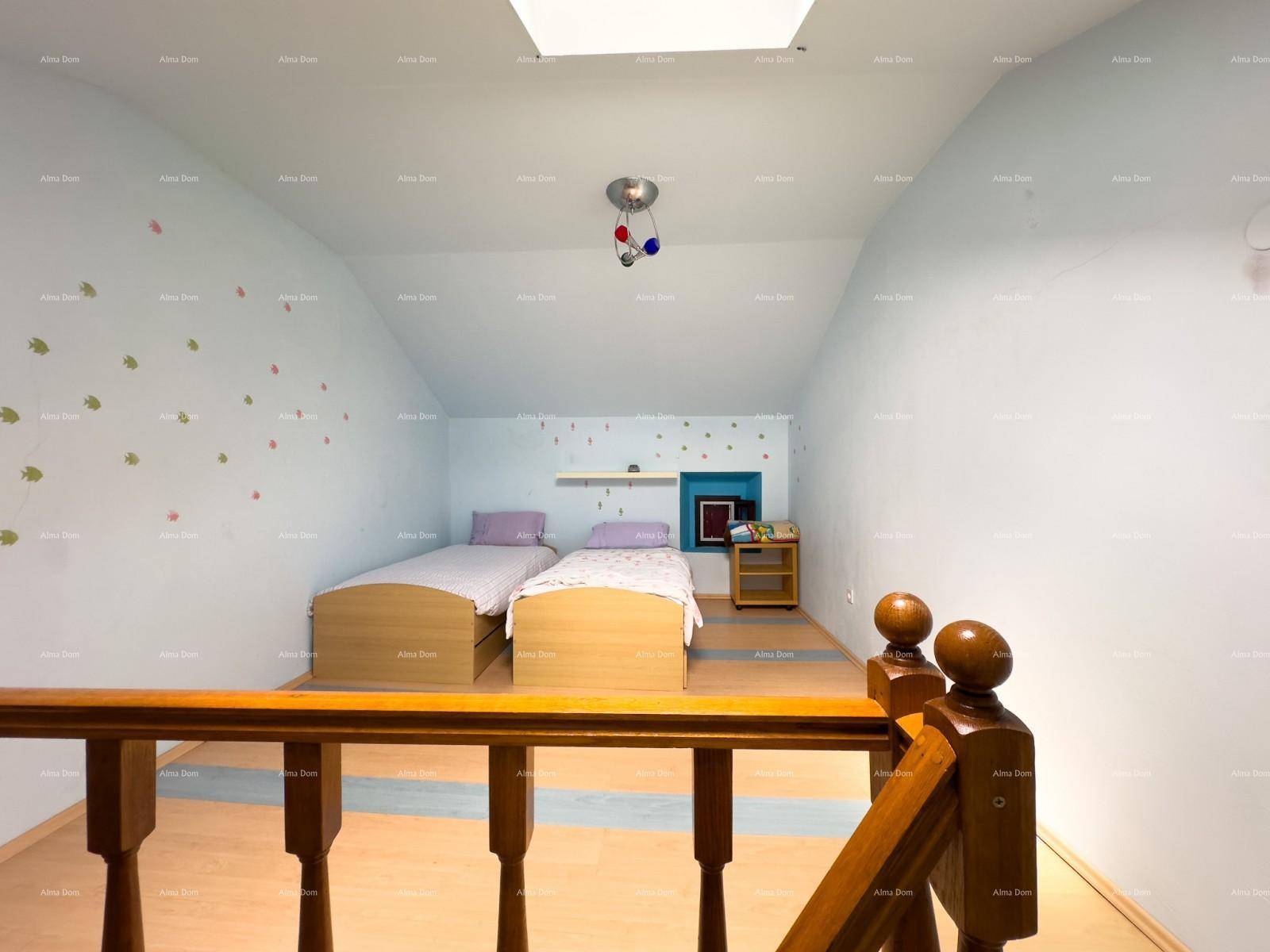 Dachgeschoss-Schlafzimmer mit zwei Betten, Holzboden und einem Dachfenster für natürliches Licht.