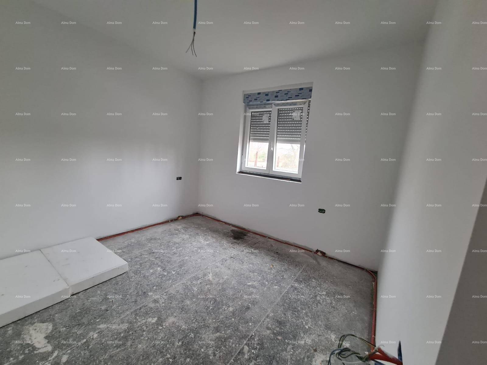 Schlafzimmer im Rohbau mit sichtbaren Leitungen und einem Fenster mit geschlossenem Rollladen.