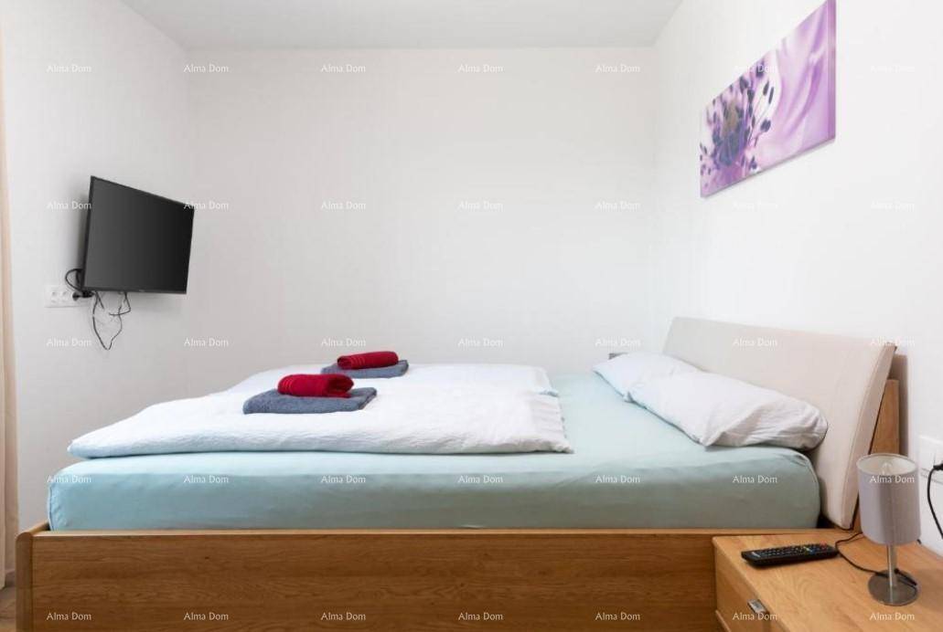 Helles Schlafzimmer mit hellem Holzdoppelbett und an der Wand montiertem Fernseher.