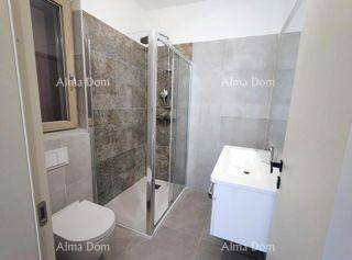 Helles Badezimmer mit Dusche, WC, Einzelwaschbecken und Fenster für Tageslicht.