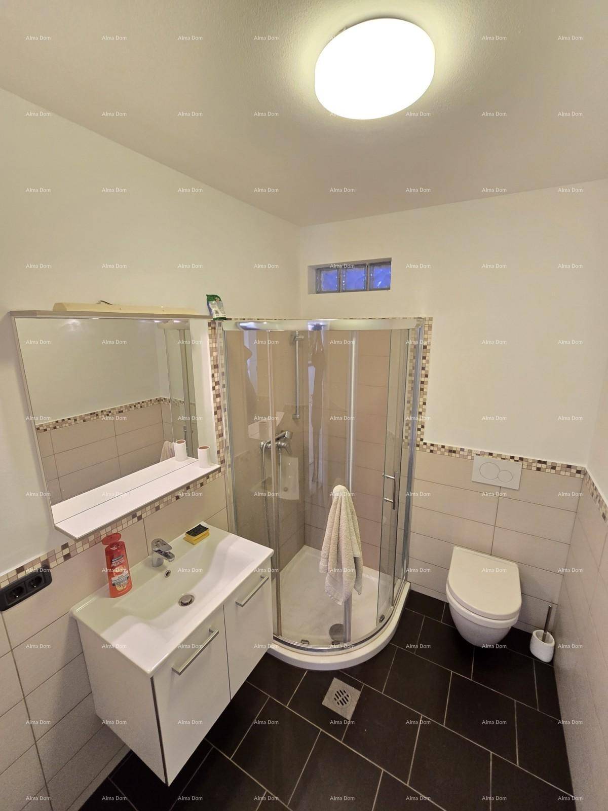 Badezimmer mit Duschkabine, Waschtisch und WC, gefliest in dunklen und hellen Tönen.