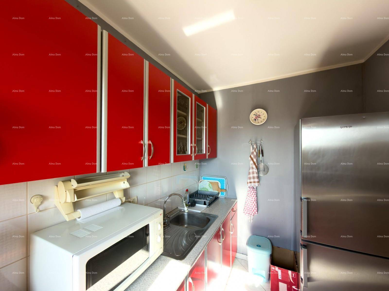 Funktionale Küche mit roten Schränken, Mikrowelle und Kühlschrank.