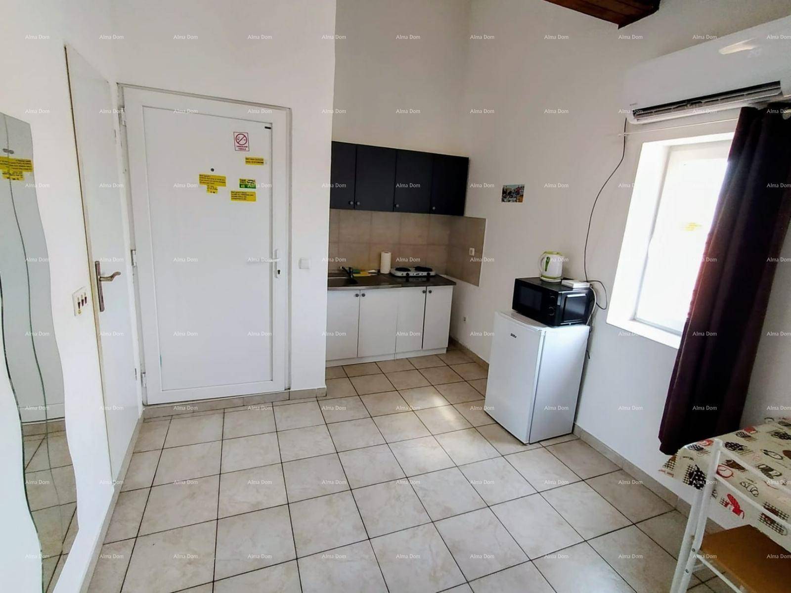 Funktionale Küchenzeile mit Essbereich und Fliesenboden in einem Studio-Apartment.
