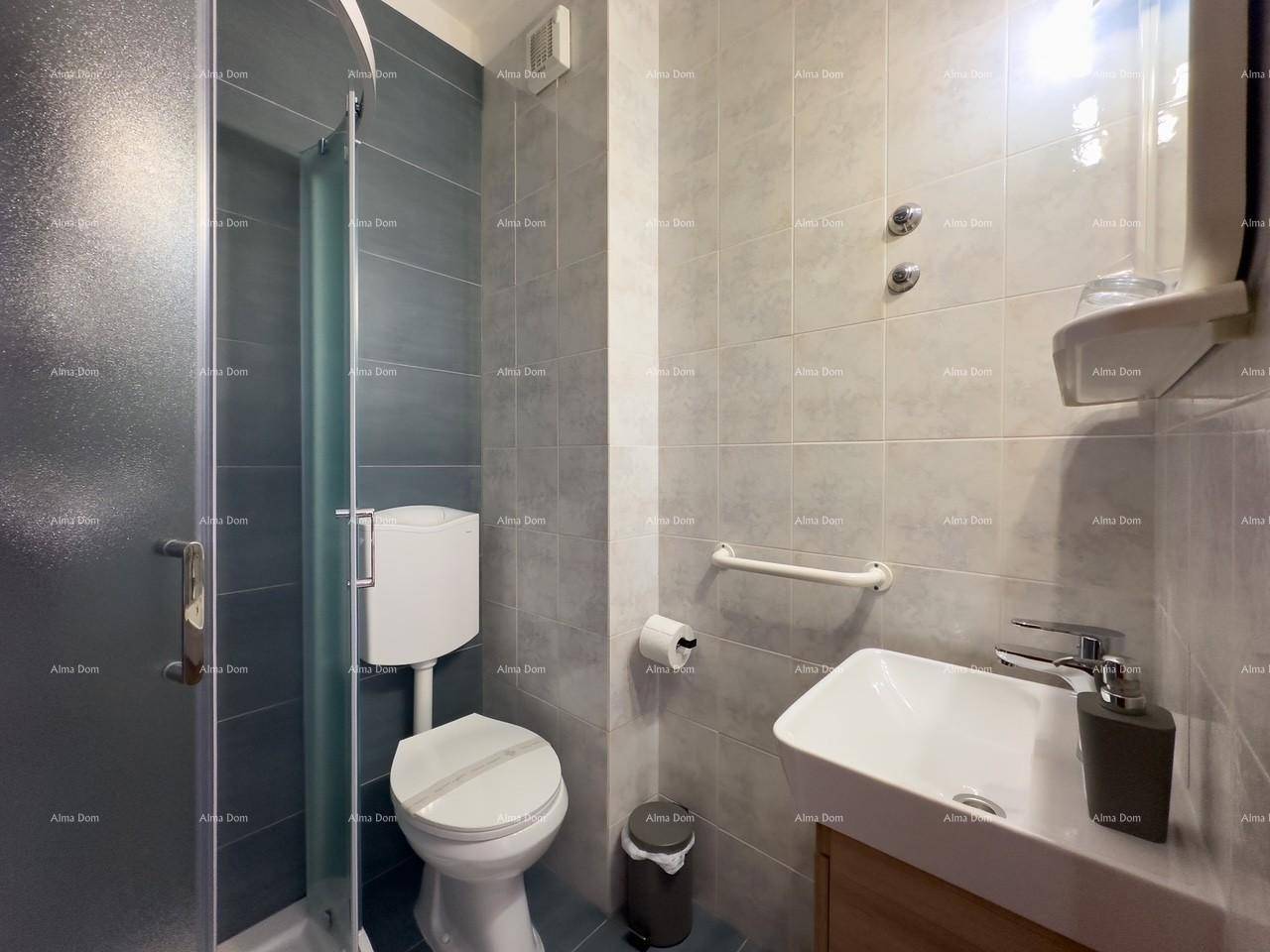 Modernes Badezimmer mit Duschkabine, WC und Waschbecken, ausgestattet mit grauen Wandfliesen und Haltegriff.
