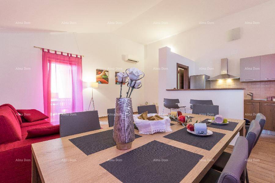 Offener Wohn-Essbereich mit rotem Sofa, Esstisch und Blick auf die halboffene Küche.