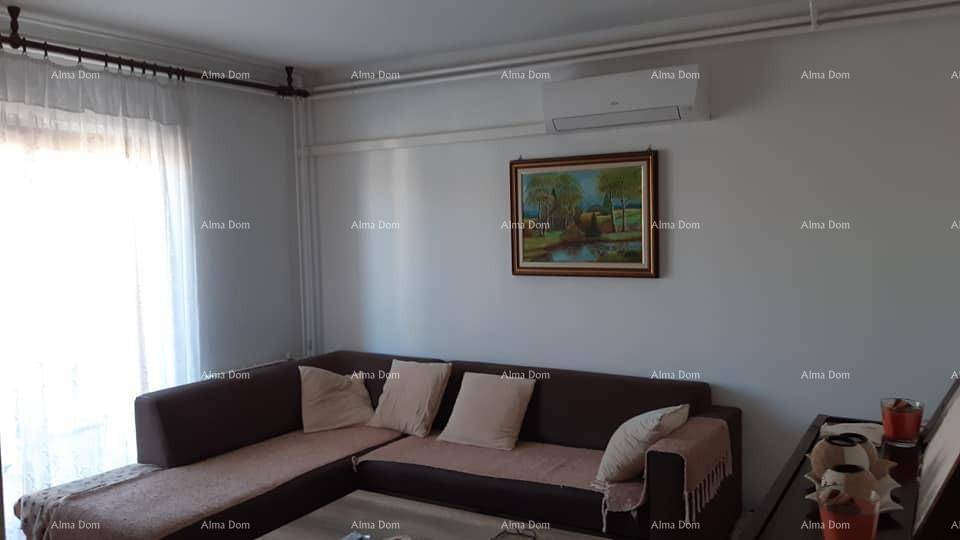 Wohnzimmer mit bequemer Eckcouch, einem Gemälde an der Wand und viel Tageslicht durch die Balkontür.