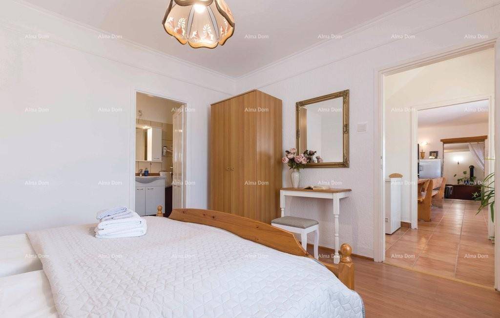 Schlafzimmer mit Holzboden, Doppelbett und Zugang zu Badezimmer und Wohnbereich.