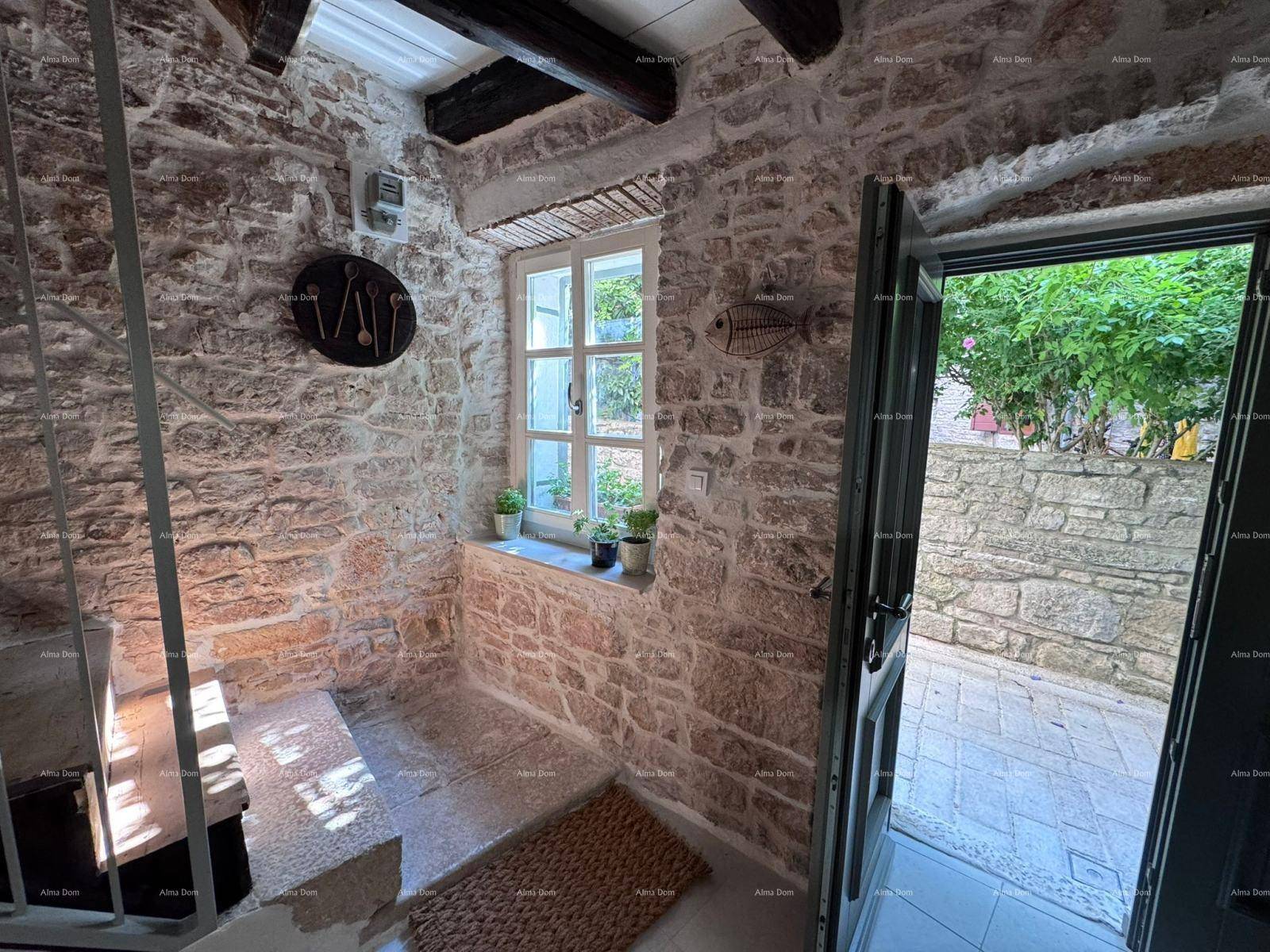 Eingangsbereich mit rustikalen Steinwänden, Fenster und Zugang zu einem gepflasterten Außenbereich.
