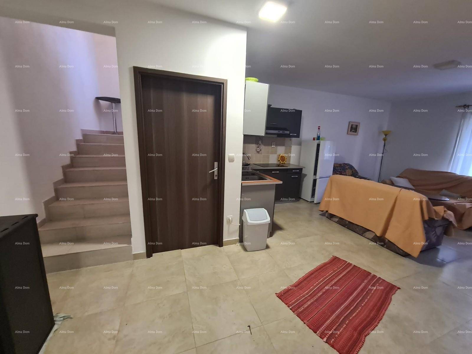 Offener Wohnbereich mit integrierter Küchenzeile, Treppe und hellem Fliesenboden.