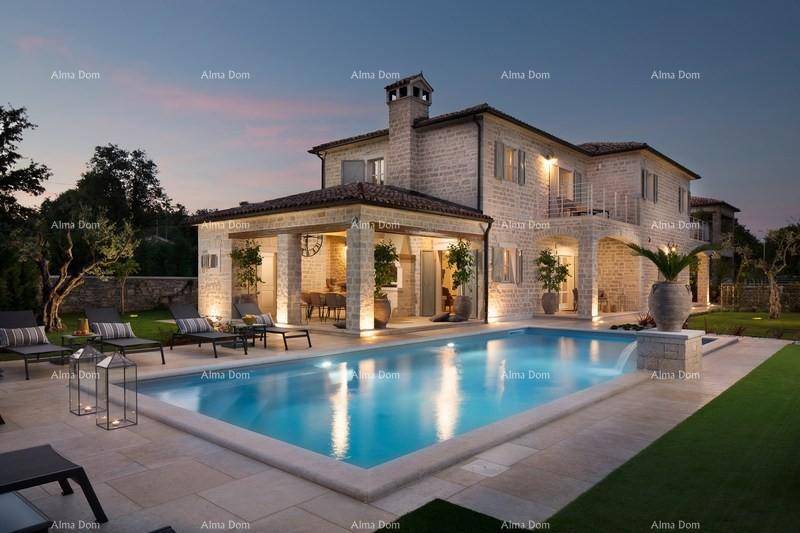 Luxuriöses Steinhaus mit großem Pool und beleuchtetem Garten bei Einbruch der Dunkelheit.