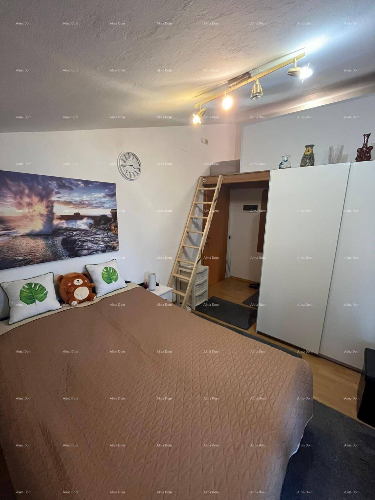 Schlafzimmer mit Doppelbett, Wandbild und einer Holzleiter, die zu einem erhöhten Schlafbereich führt.