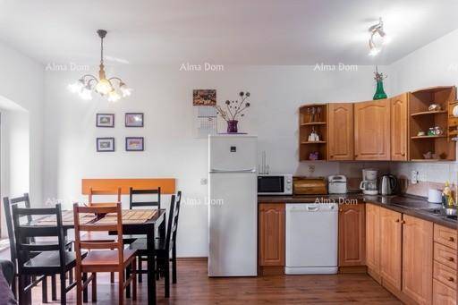 Offener Wohn-Essbereich mit Holzküche, Esstisch und Kühlschrank, ideal für geselliges Beisammensein.