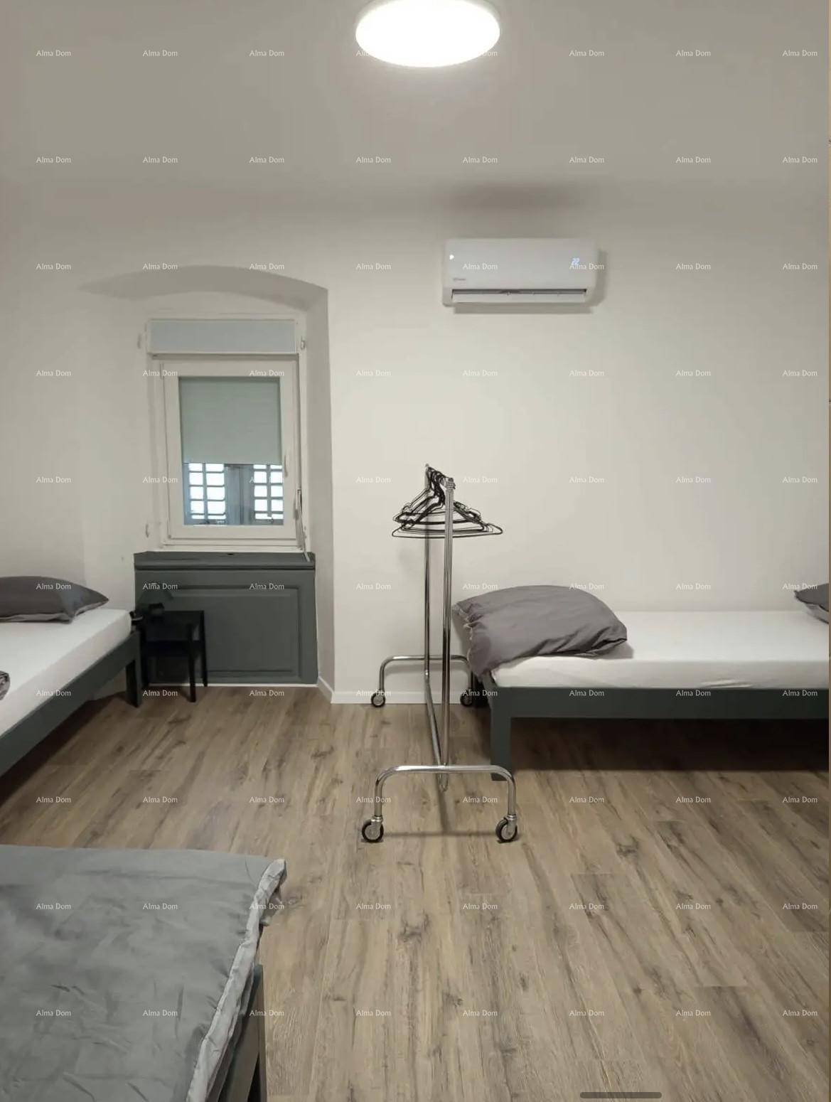 Helles Schlafzimmer mit Einzelbetten, Kleiderständer und Klimaanlage.