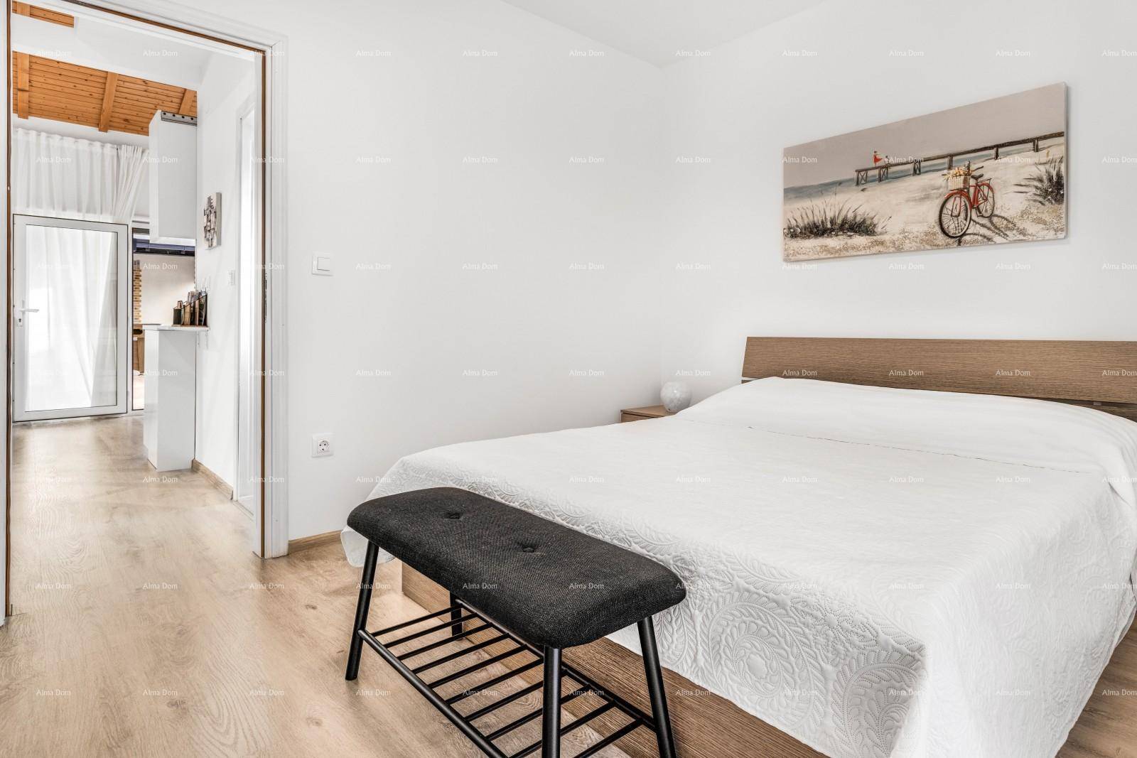Schlafzimmer mit Holzbett, hellem Boden und Zugang zu einem weiteren Raum.