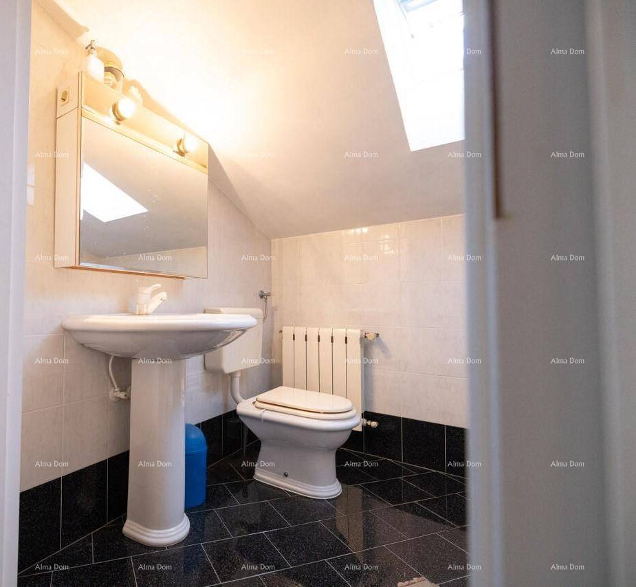 Badezimmer im Dachgeschoss mit WC, Waschbecken und natürlichem Licht durch das Dachfenster.