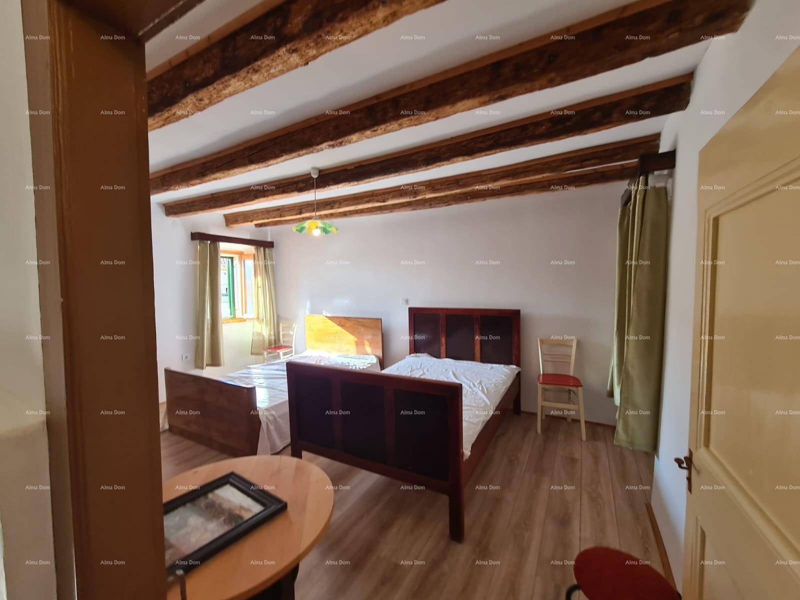 Schlafzimmer mit zwei Einzelbetten, kleinem Tisch und rustikaler Holzbalkendecke.